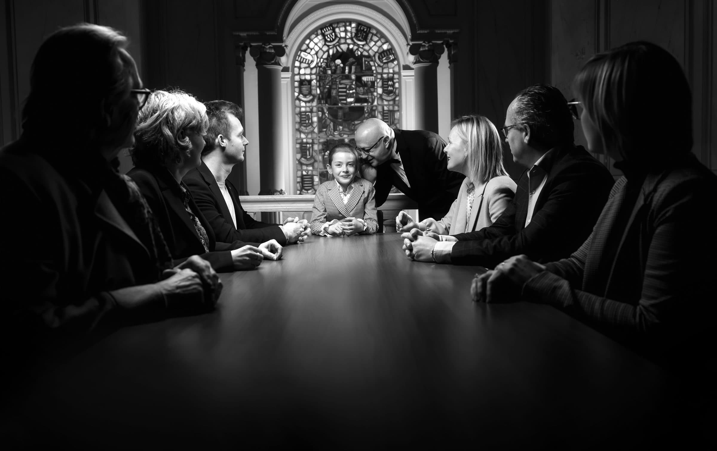 Een familie in gesprek rond een lange tafel