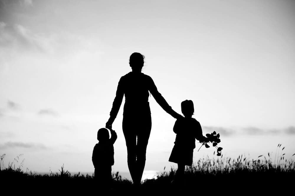 Silhouet van een ouder die met twee kinderen wandelt