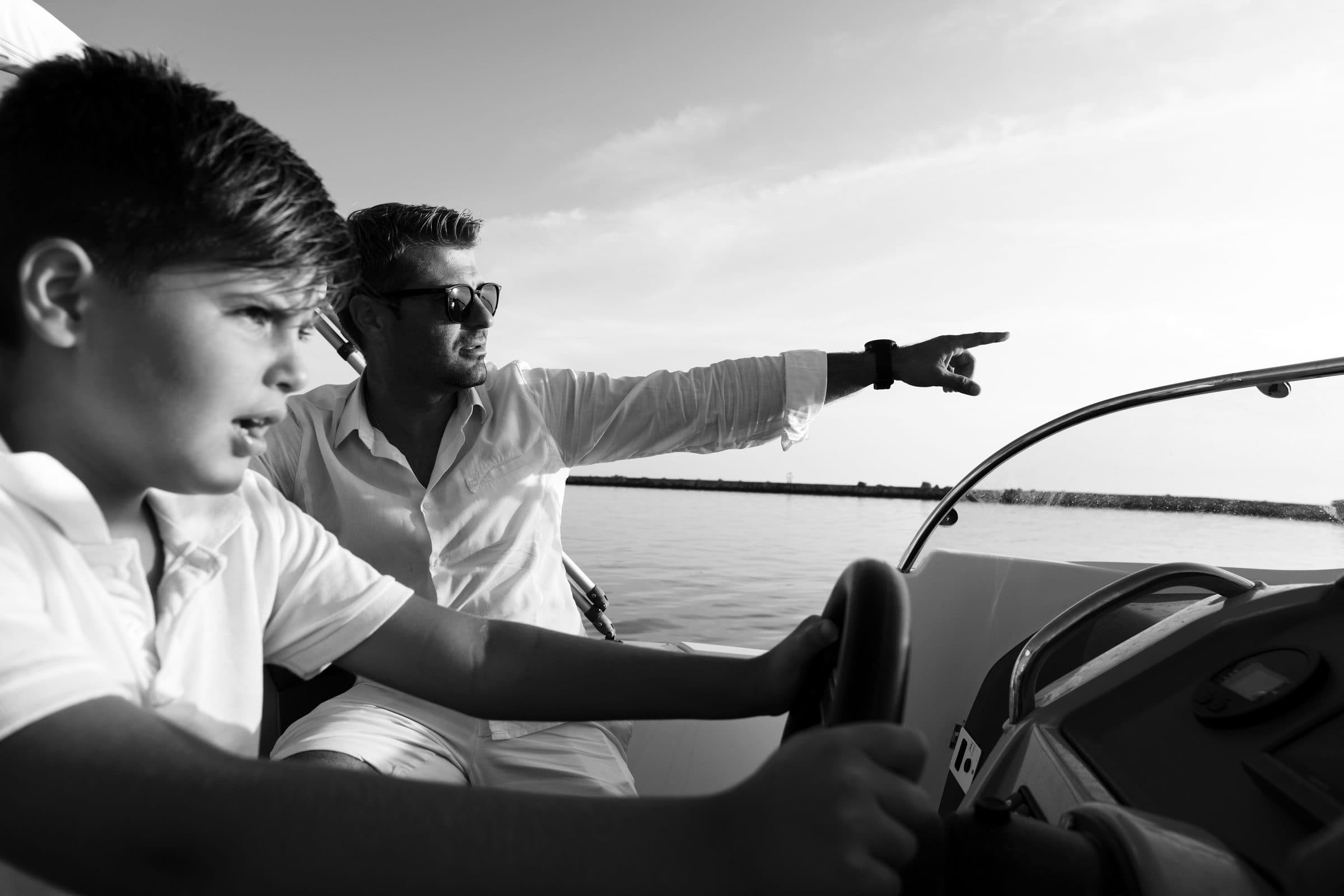 Een vader wijst zijn zoon de koers aan vanop een boot
